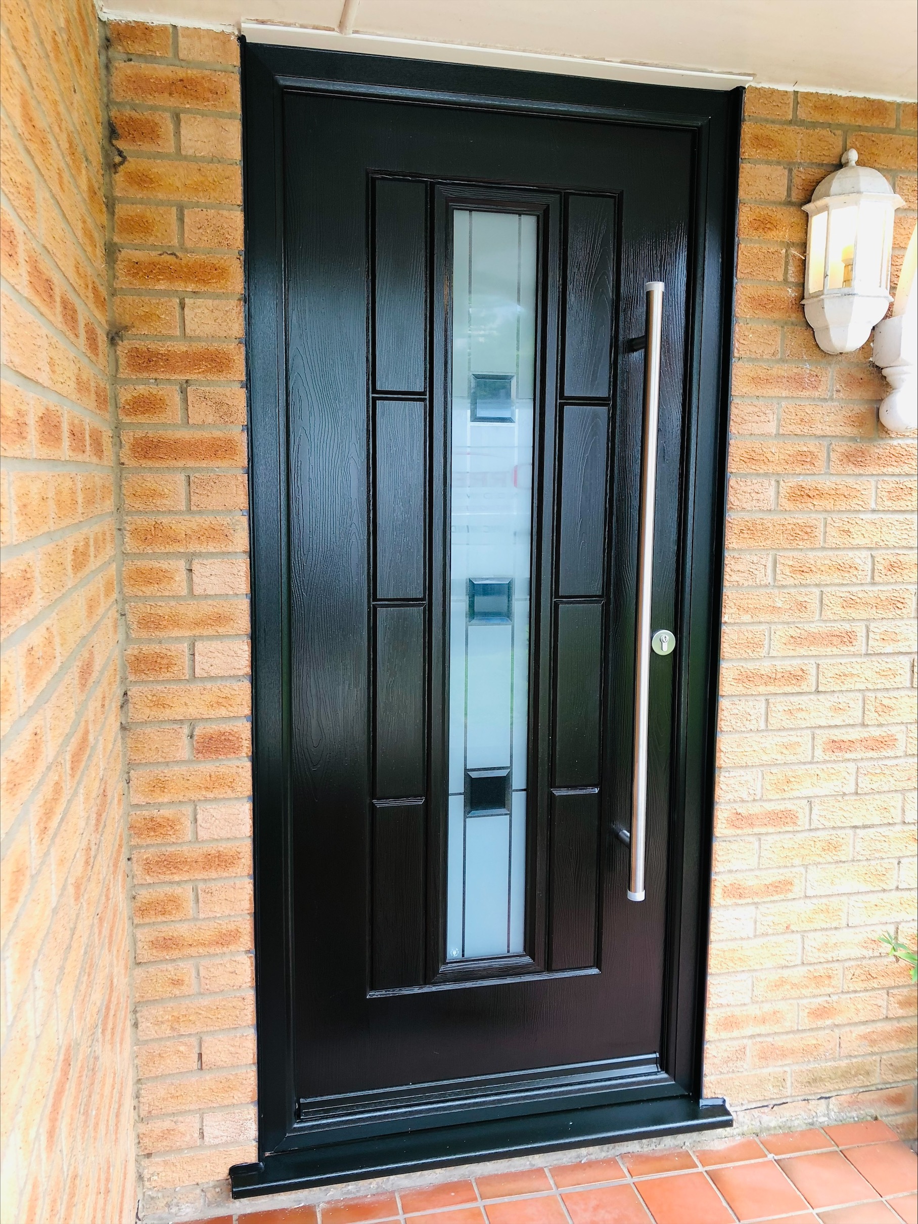 Modern black composite front door with long bar handle
