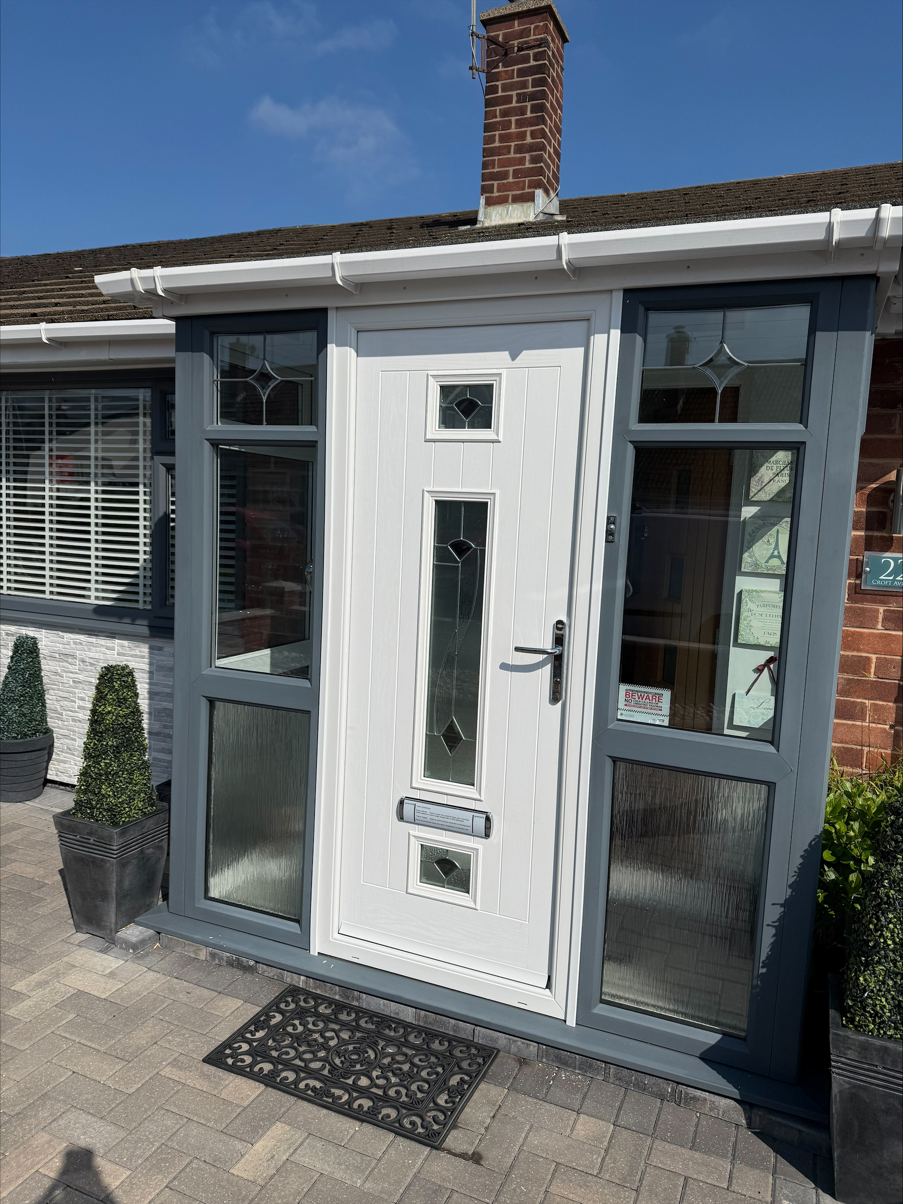White composite front door with grey UPVC porch and decorative glass